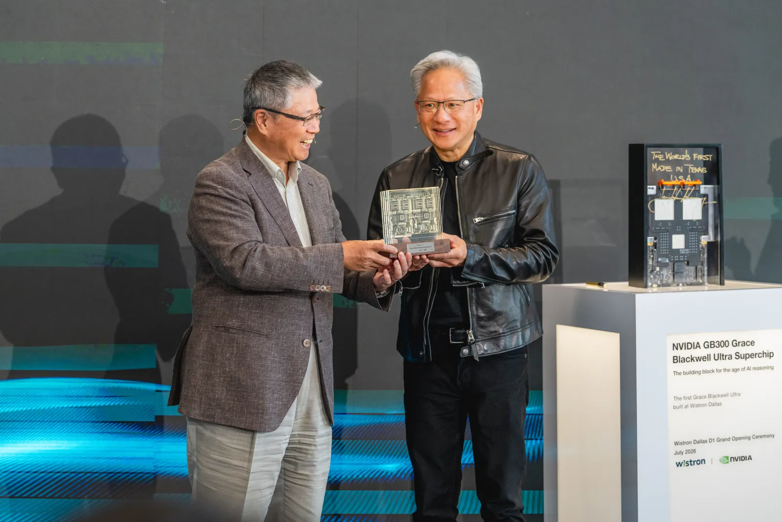 Wistron and NVIDIA executives holding a commemorative award beside the GB200 Superchip display